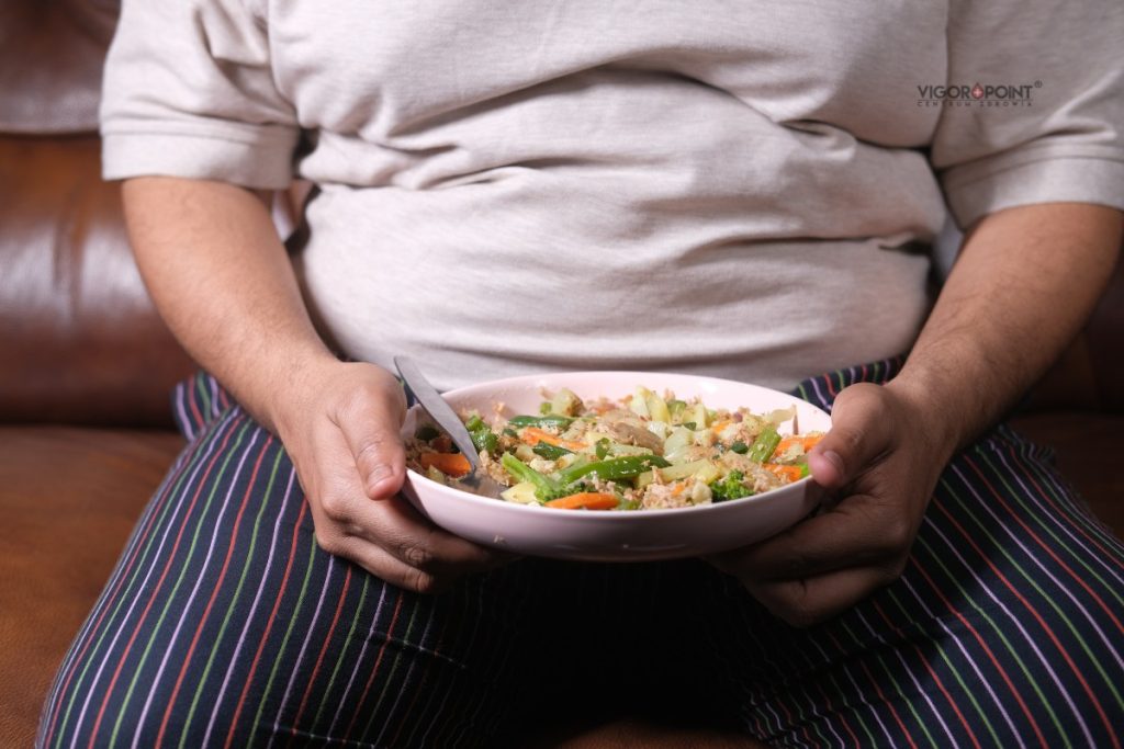 Otyły mężczyzna jedzący warzywa - TRT a redukcja tłuszczu