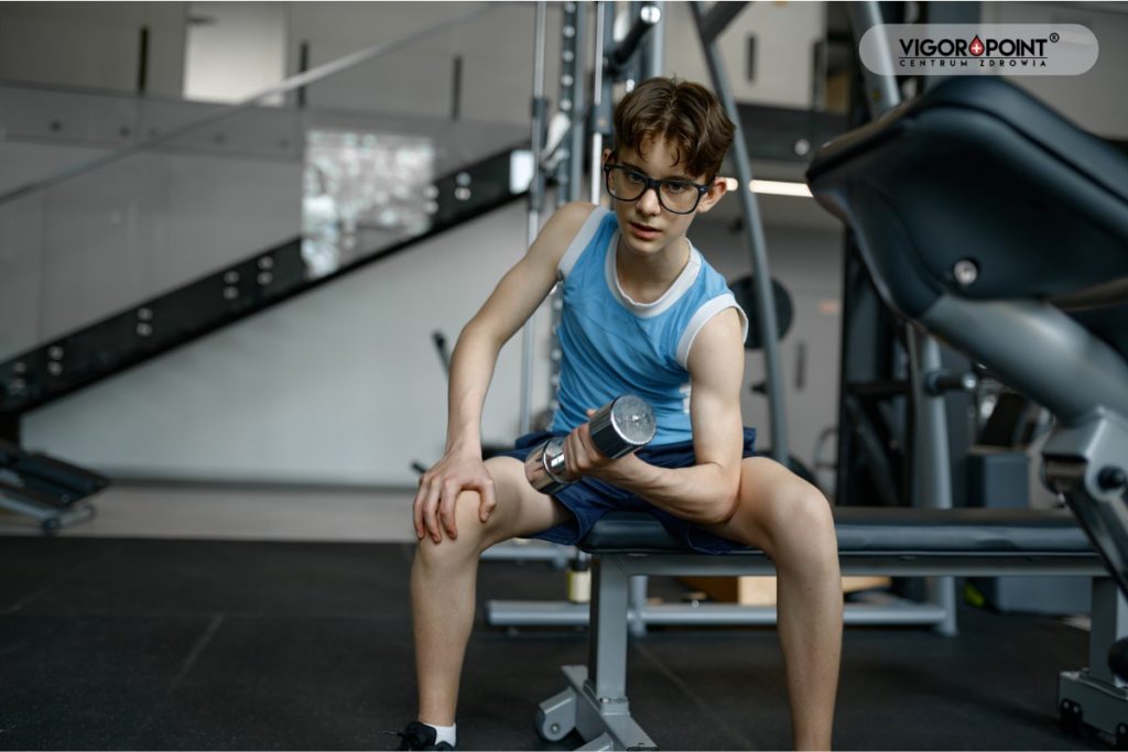 Szczupły chłopak ćwiczy na siłowni. Skinny fat - otyłość sarkopieczna
