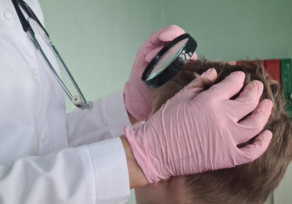 Dermatolog-trycholog sprawdza stan skóry głowy pacjenta